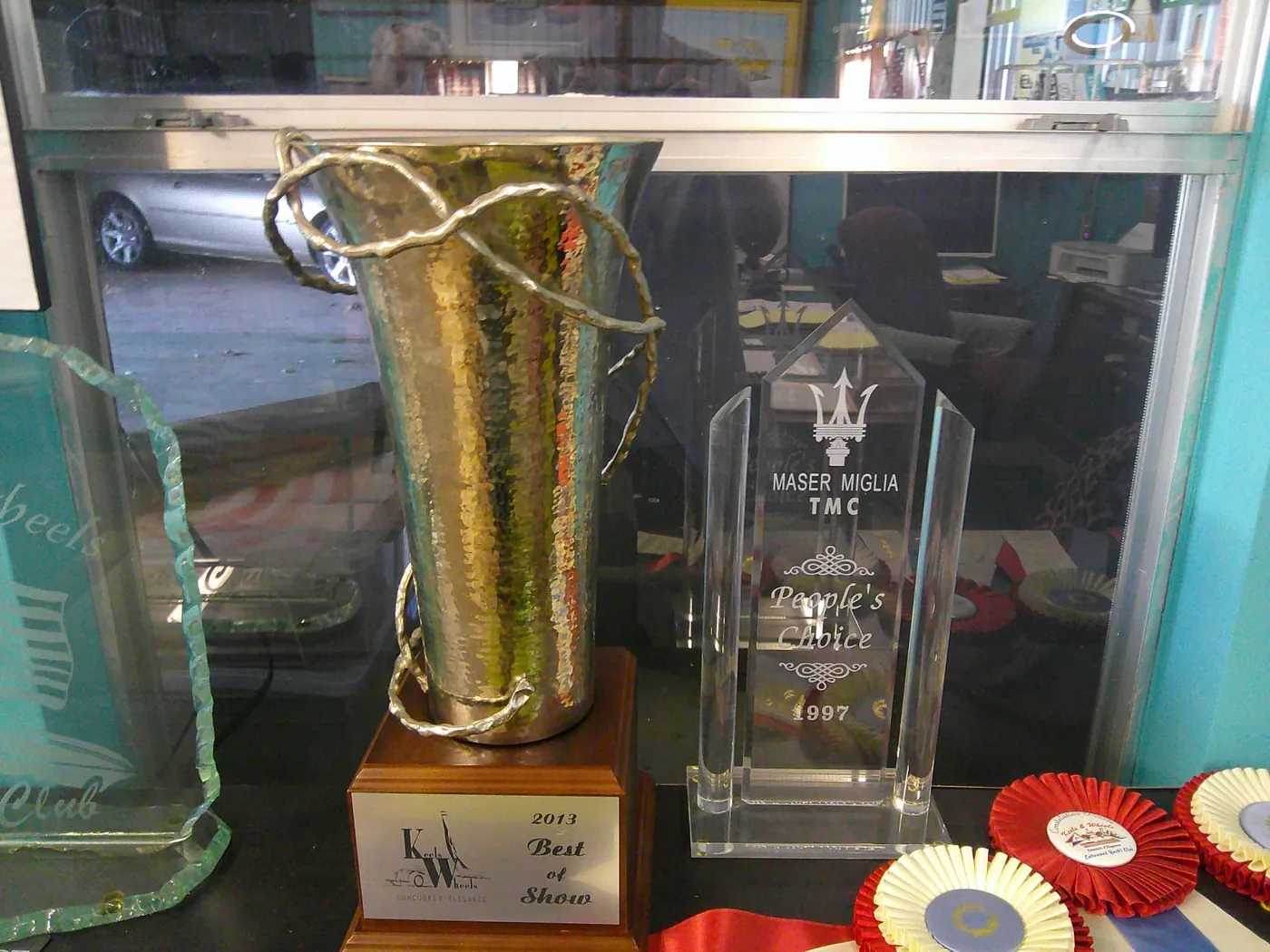 2013 Keels & Wheels Best of Show trophy beside a 1997 Maser Miglia People's Choice award.