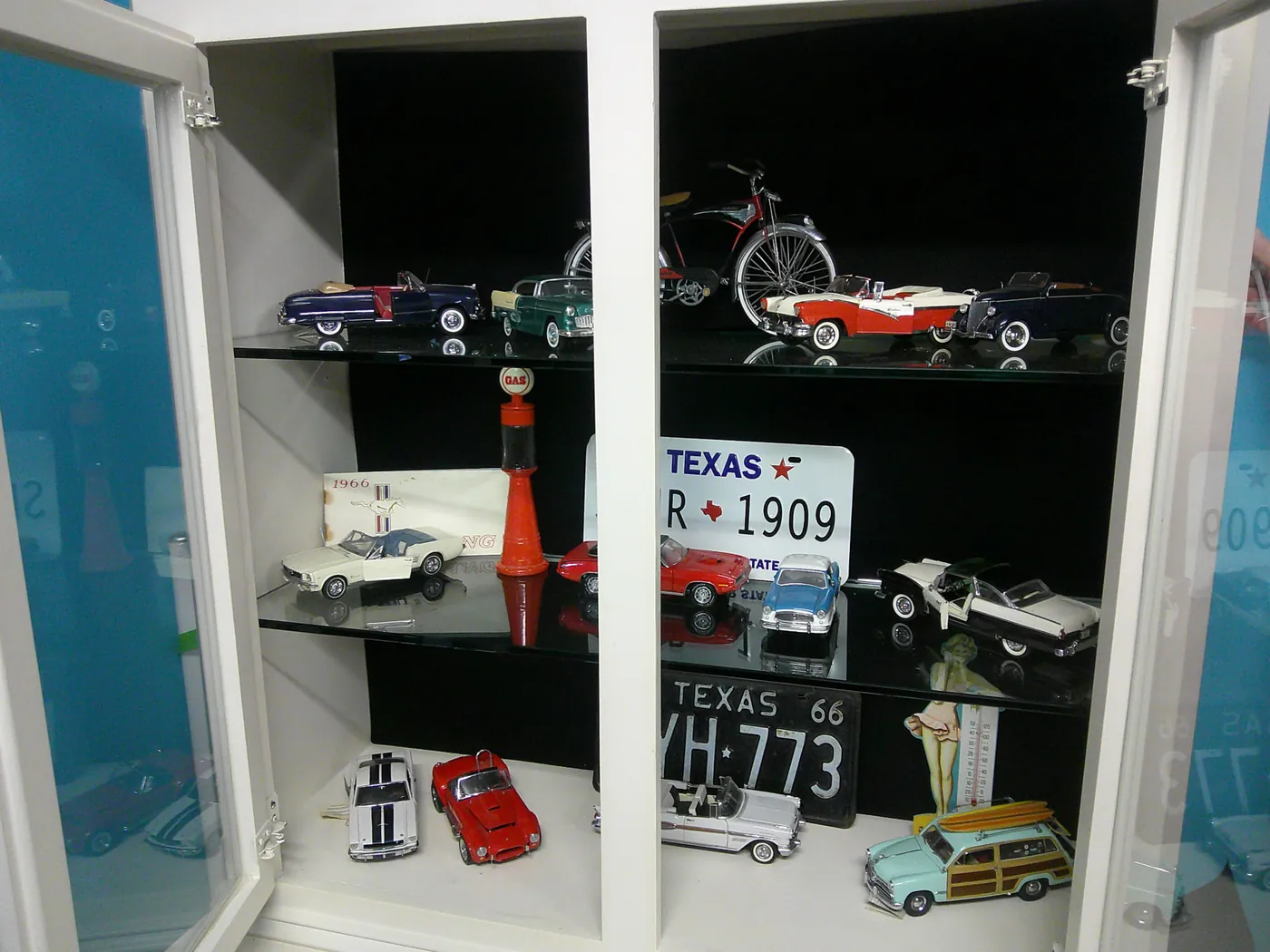 Display cabinet of scale model classic cars and vintage Texas license plates.